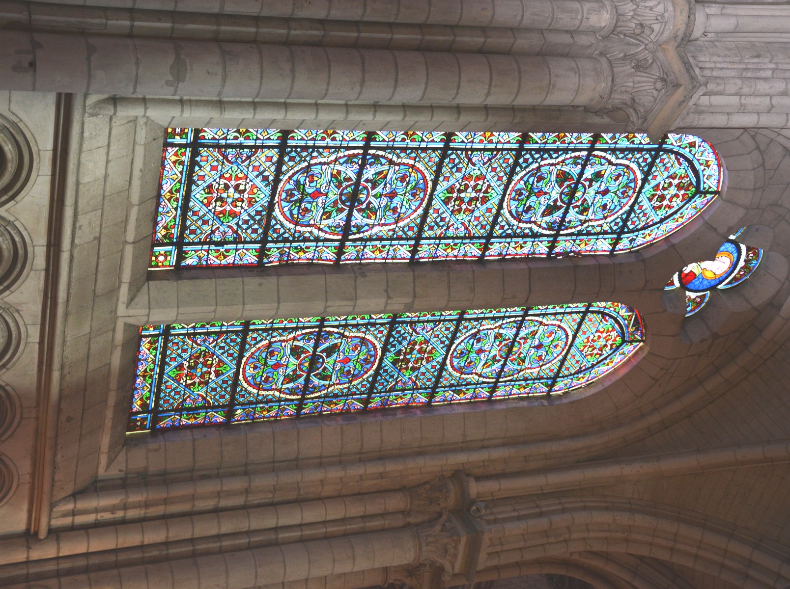 Cathédrale de Saint-Omer | Déambulatoire vitraux travée 05, Deux vitraux à deux formes couronnés chacun par un quatrefeuille. Décor géométrique ; bustes de saint Pierre et saint Paul dans les quatrefeuilles. 1874 ; ateliers A. Lusson et L. Lefèvre (Paris). Hauteur : 5,00 m environ. Largeur : 3,00 m environ.