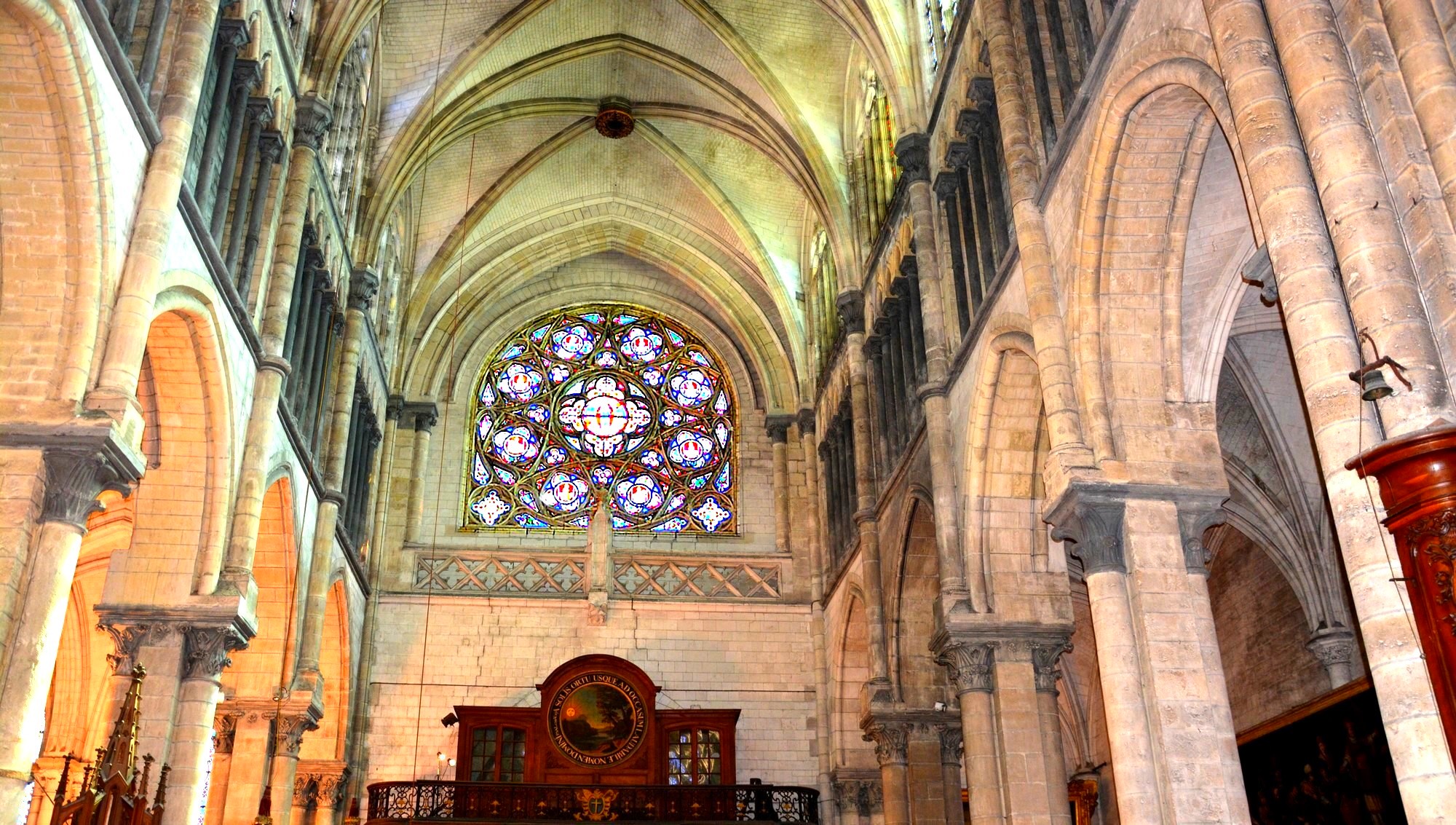 Cathédrale de Saint-Omer | rosace Sud | Rose à remplage central circulaire, encadré de huit grands quadrilobes et huits petits. Deux écoinçons dans le bas forment une base horizontale. Verre à dominante rouge et bleue. Aux extrémités inférieures, deux grands quadrilobes. Les espaces intermédiaires sont remplis par des mouchettes et de très petits écoinçons.